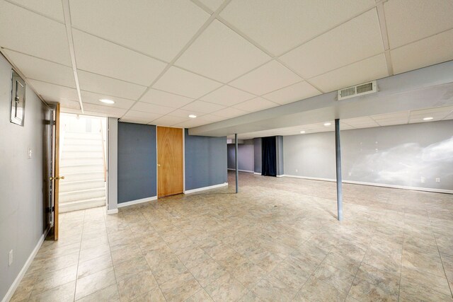 finished basement featuring visible vents, baseboards, and a drop ceiling