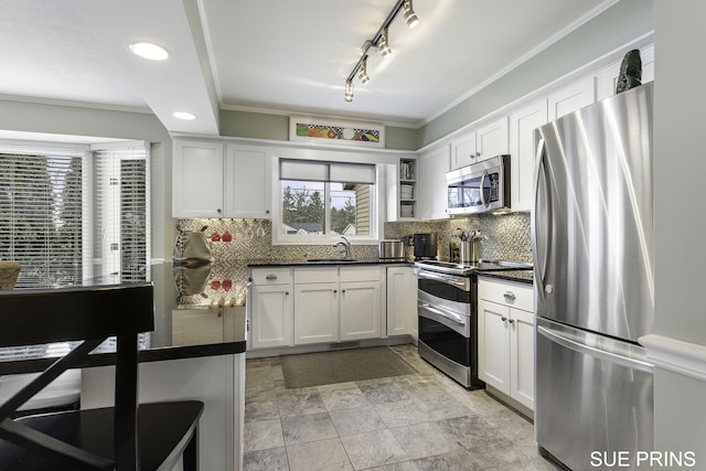 kitchen with dark countertops, white cabinets, tasteful backsplash, and stainless steel appliances