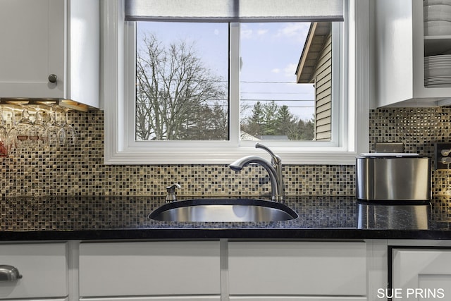 kitchen with tasteful backsplash, white cabinets, and a sink