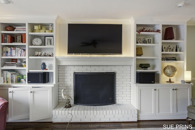 living room with a brick fireplace and wood finished floors