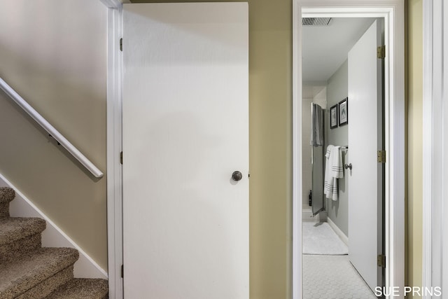 hall with visible vents, stairway, and baseboards