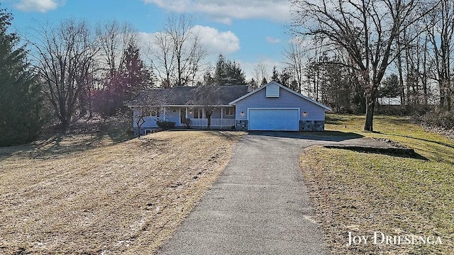 ranch-style home featuring stone siding, driveway, an attached garage, and a front lawn