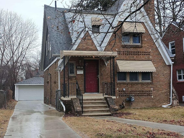 tudor house with brick siding, a garage, a shingled roof, and an outdoor structure