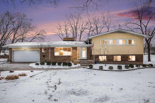 tri-level home with a garage, driveway, and a chimney