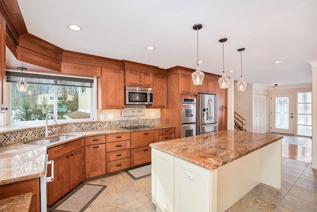 kitchen featuring a healthy amount of sunlight, brown cabinetry, a sink, stainless steel appliances, and tasteful backsplash