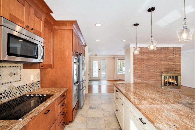 kitchen featuring light stone counters, backsplash, brown cabinetry, and appliances with stainless steel finishes