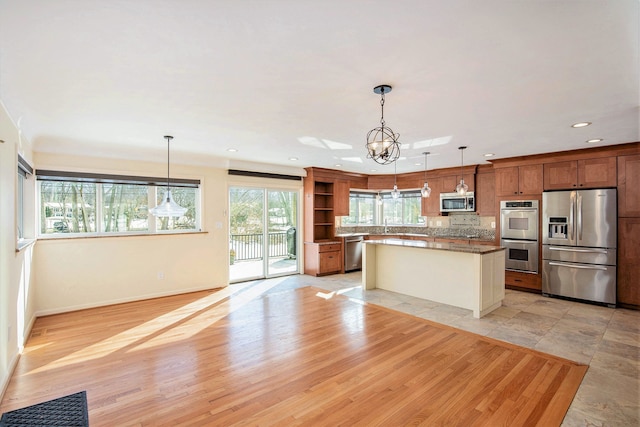 kitchen featuring hanging light fixtures, appliances with stainless steel finishes, light wood-style floors, and open shelves