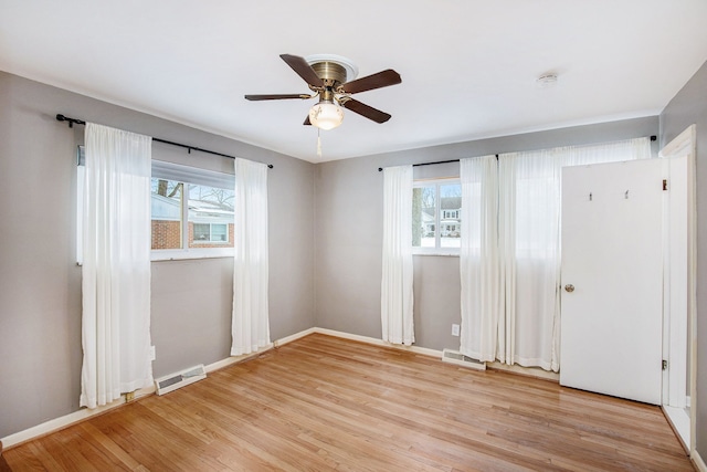 empty room with a wealth of natural light, visible vents, and light wood finished floors