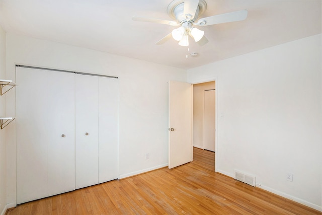 unfurnished bedroom featuring a ceiling fan, visible vents, baseboards, light wood-style floors, and a closet