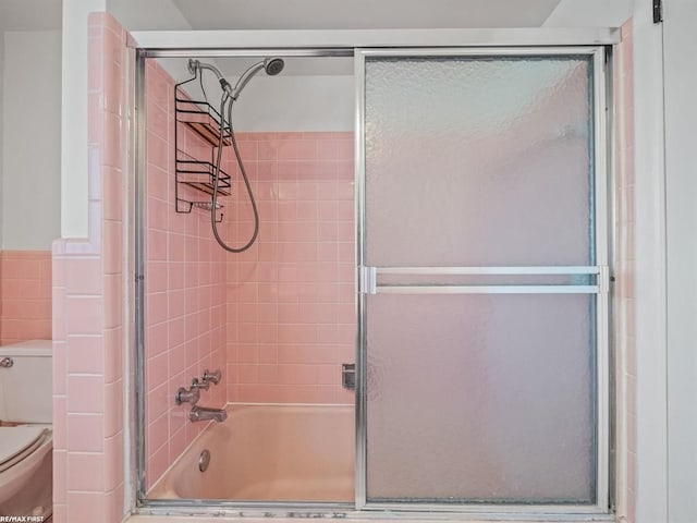 bathroom with toilet and bath / shower combo with glass door