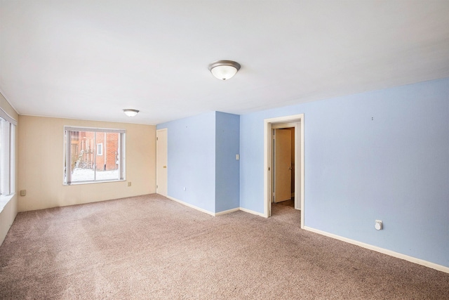 carpeted empty room featuring baseboards