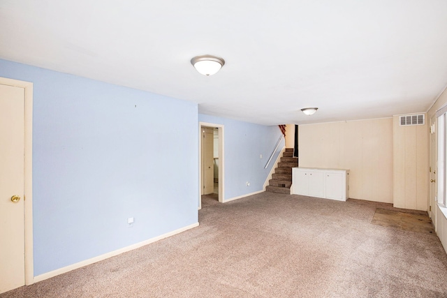 basement with carpet flooring, baseboards, stairs, and visible vents