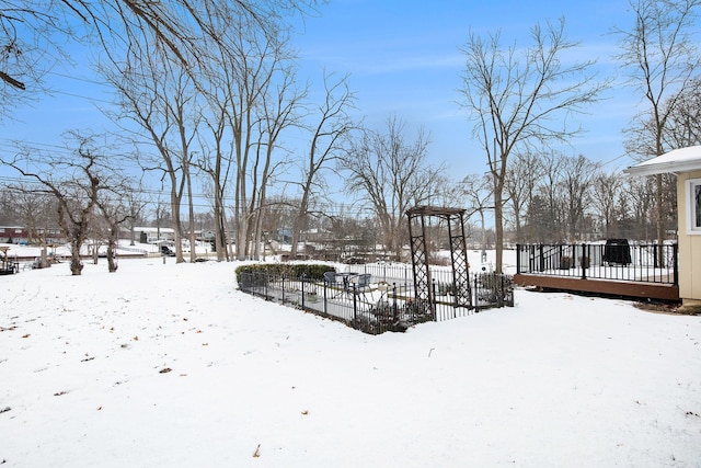 yard layered in snow featuring a deck and fence