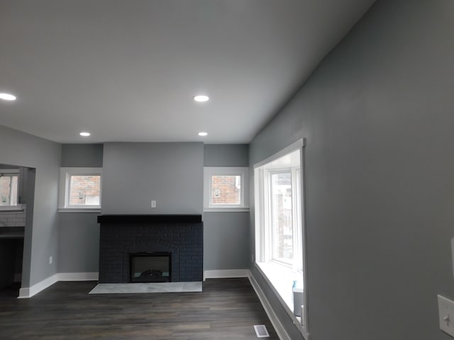 living area featuring plenty of natural light, a fireplace, and dark wood-style flooring