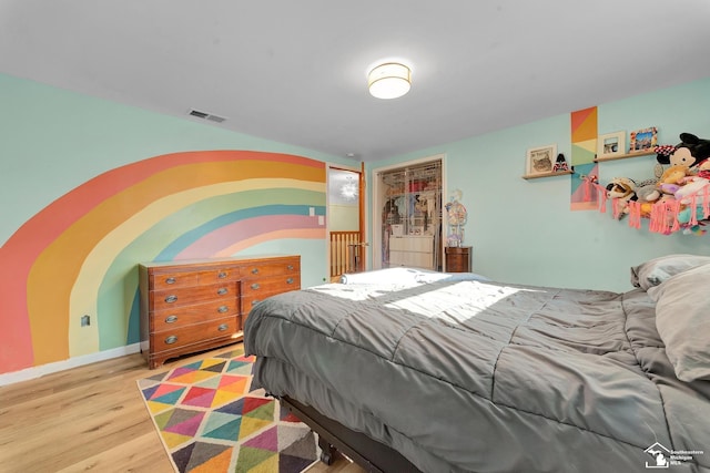 bedroom with visible vents, baseboards, and wood finished floors