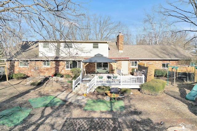 rear view of property with a wooden deck, brick siding, and a chimney