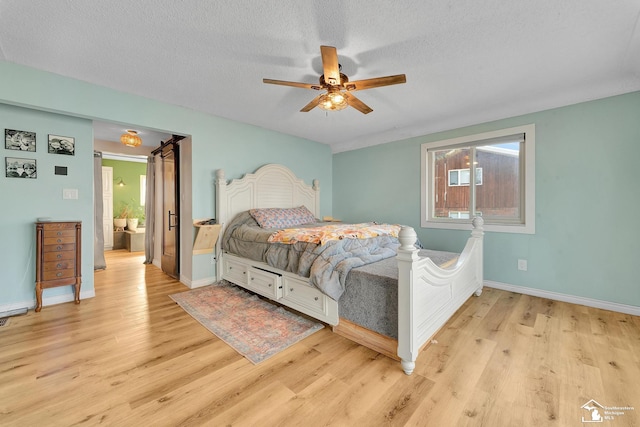 bedroom featuring a ceiling fan, baseboards, light wood-type flooring, and a textured ceiling