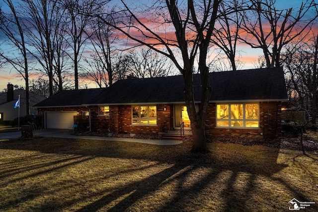 view of front facade with a front lawn, brick siding, an attached garage, and a shingled roof