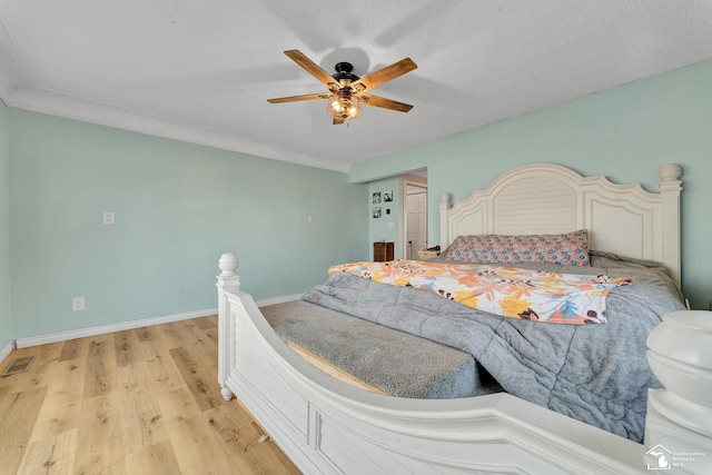 bedroom with visible vents, a textured ceiling, light wood finished floors, baseboards, and ceiling fan