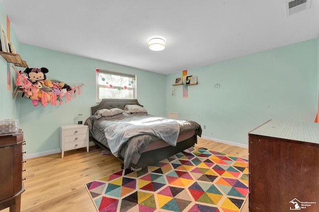 bedroom featuring visible vents, baseboards, and light wood finished floors