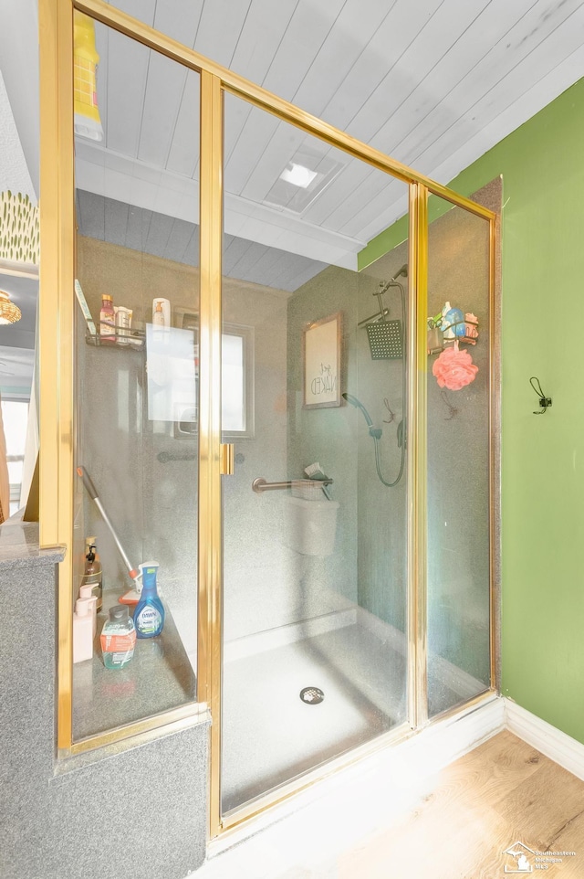 full bathroom with wood finished floors, baseboards, beam ceiling, a shower stall, and wooden ceiling