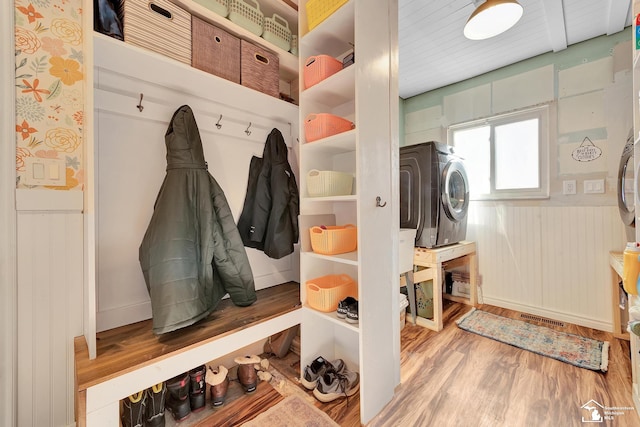 mudroom with stacked washer / dryer, a wainscoted wall, visible vents, and wood finished floors