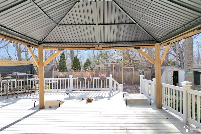 wooden terrace featuring a storage shed, an outbuilding, and a fenced backyard