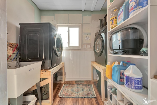 laundry room with laundry area, washer and dryer, and wood finished floors