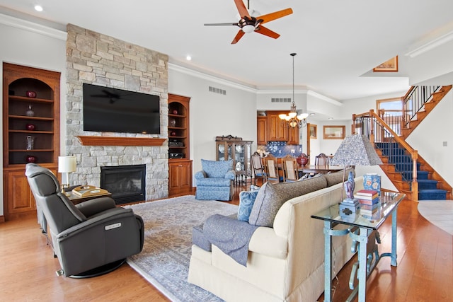 living room featuring visible vents, light wood-style floors, ornamental molding, and ceiling fan with notable chandelier