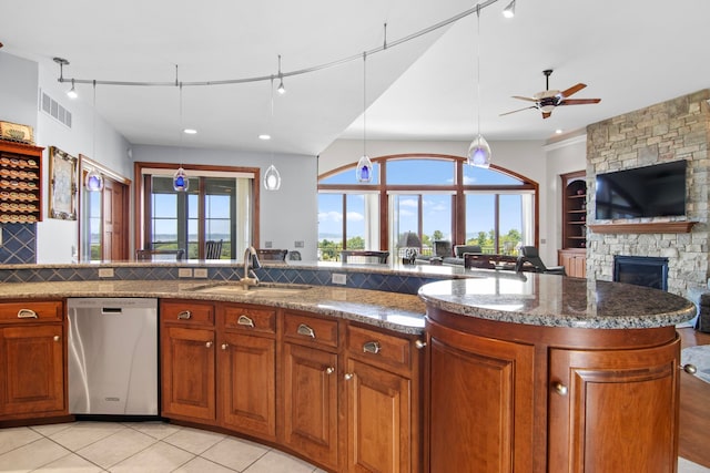 kitchen with brown cabinetry, ceiling fan, a sink, dishwasher, and open floor plan