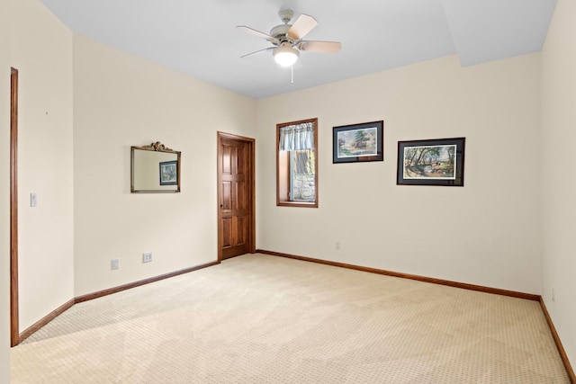 spare room with light colored carpet, a ceiling fan, and baseboards