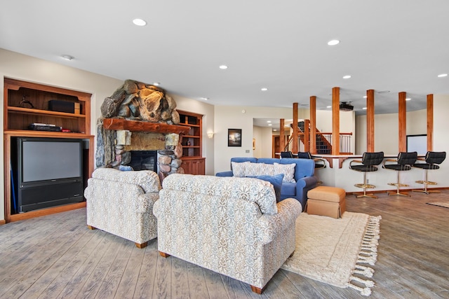 living area featuring recessed lighting, a stone fireplace, and wood finished floors
