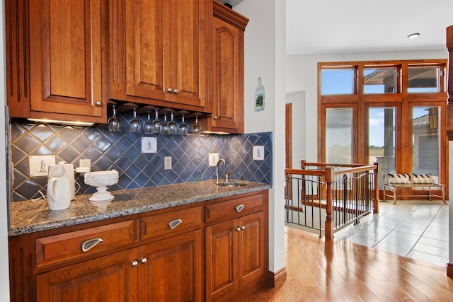 kitchen with brown cabinets, dark stone counters, and a sink