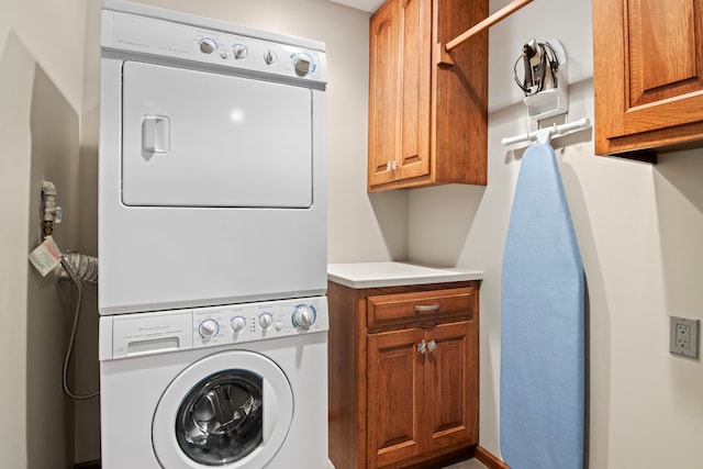 laundry room featuring cabinet space and stacked washer / dryer