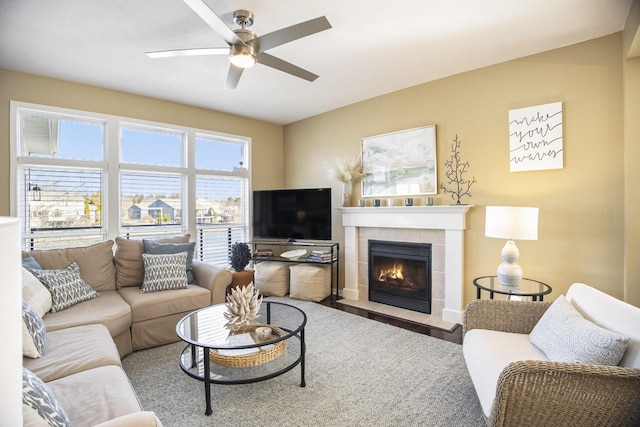 living area featuring wood finished floors, a tile fireplace, and ceiling fan