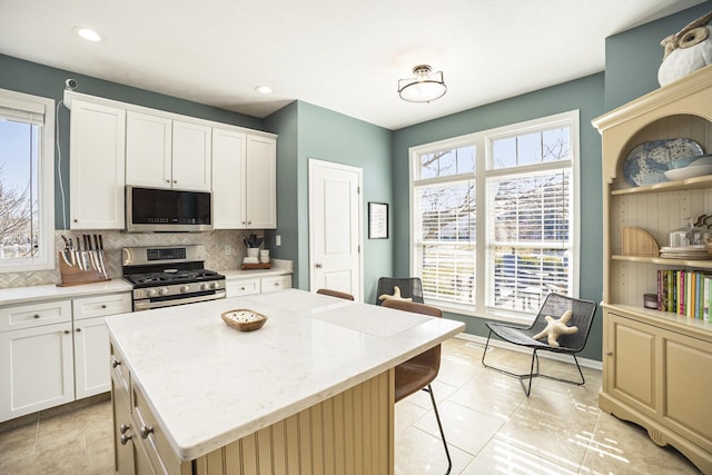 kitchen with stainless steel appliances, plenty of natural light, tasteful backsplash, and a kitchen island