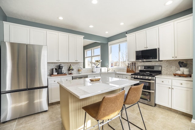 kitchen with a breakfast bar, backsplash, a center island, and stainless steel appliances