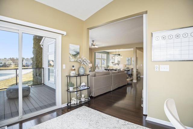 interior space featuring baseboards, a healthy amount of sunlight, wood finished floors, and vaulted ceiling