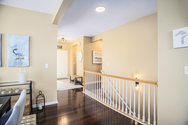 corridor with hardwood / wood-style flooring, an upstairs landing, and baseboards