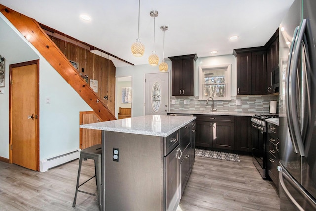 kitchen featuring a baseboard heating unit, light wood-style floors, backsplash, and stainless steel appliances