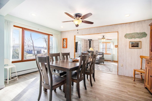 dining area featuring light wood-type flooring, a baseboard heating unit, and a wood stove