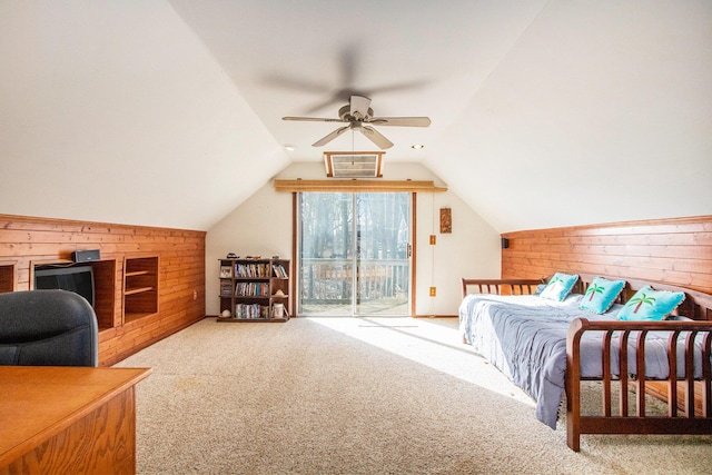 carpeted bedroom with ceiling fan, wooden walls, access to exterior, and vaulted ceiling