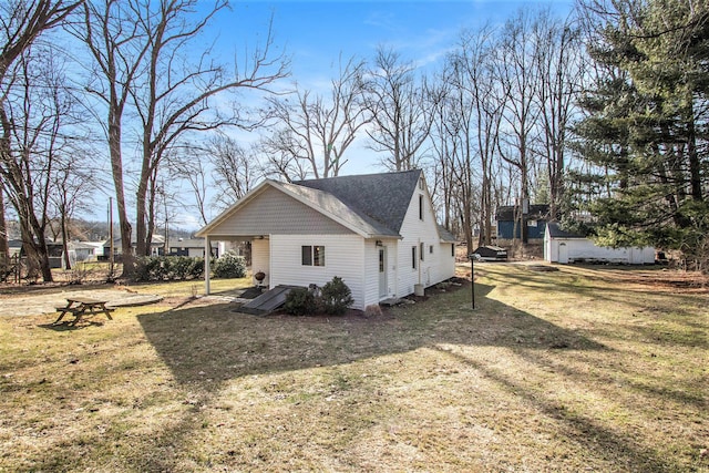 view of side of property featuring a shingled roof and a yard