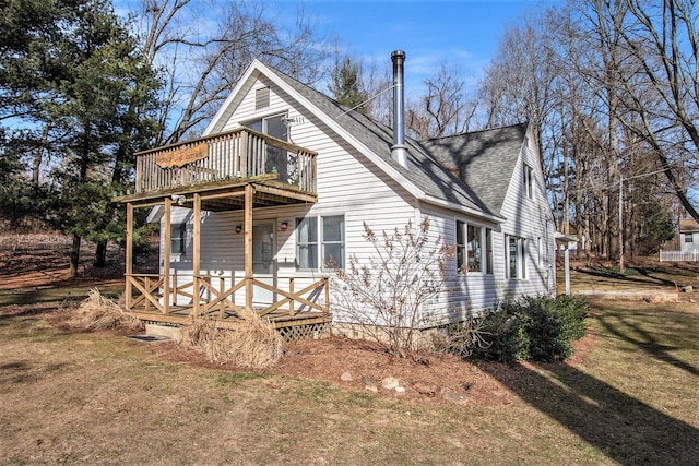 view of side of home featuring a porch, a shingled roof, and a yard