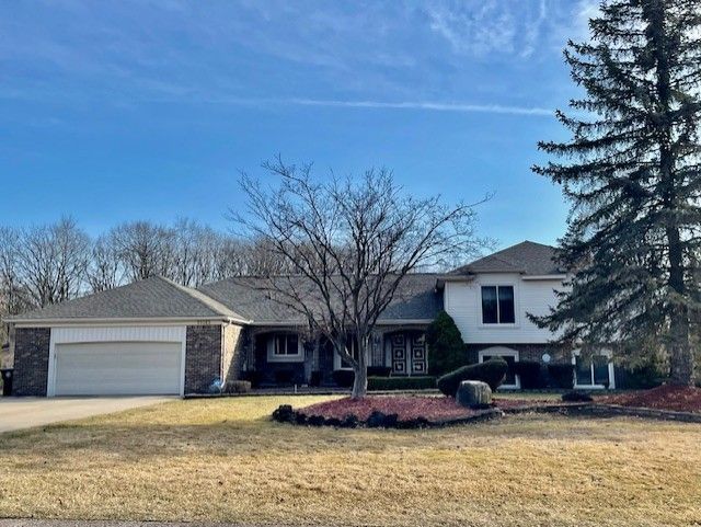 split level home with an attached garage, concrete driveway, and a front lawn