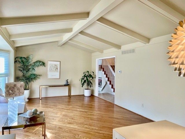 living room with stairway, vaulted ceiling with beams, visible vents, and wood finished floors