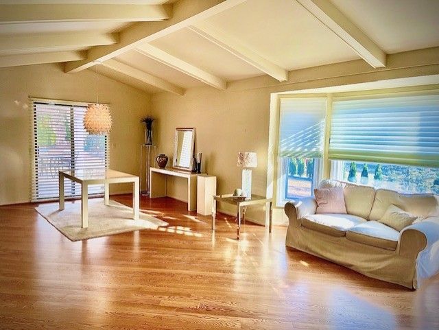 living area featuring plenty of natural light, vaulted ceiling with beams, and wood finished floors