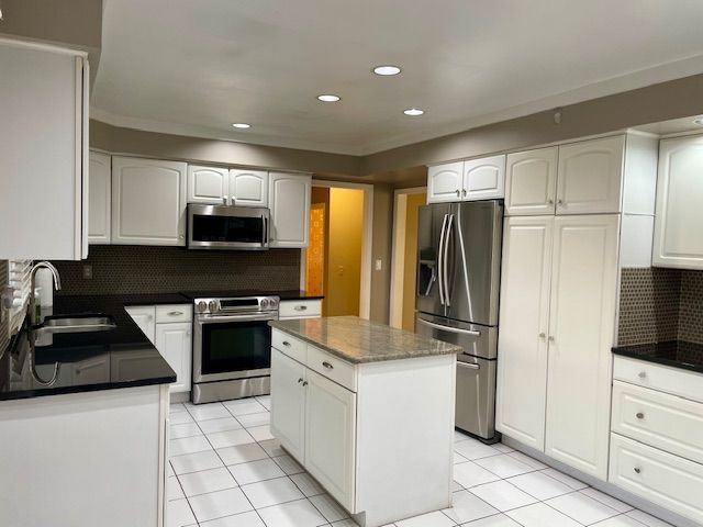 kitchen with white cabinetry, backsplash, appliances with stainless steel finishes, and a sink