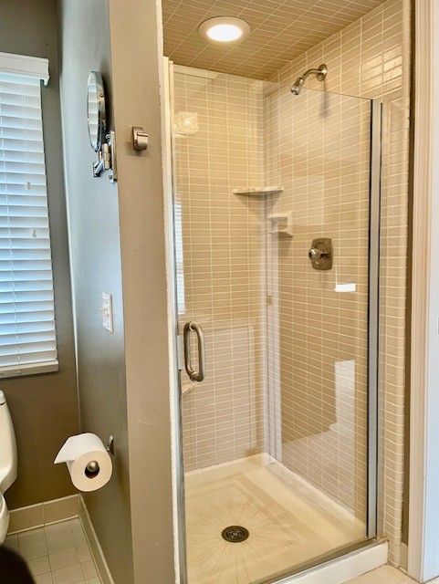 bathroom with tile patterned floors, toilet, baseboards, and a stall shower