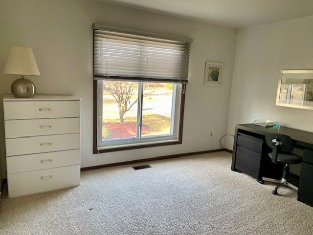 home office with visible vents, baseboards, and light colored carpet